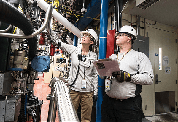 Workers in a factory wearing PSE perform safety checks of equipment